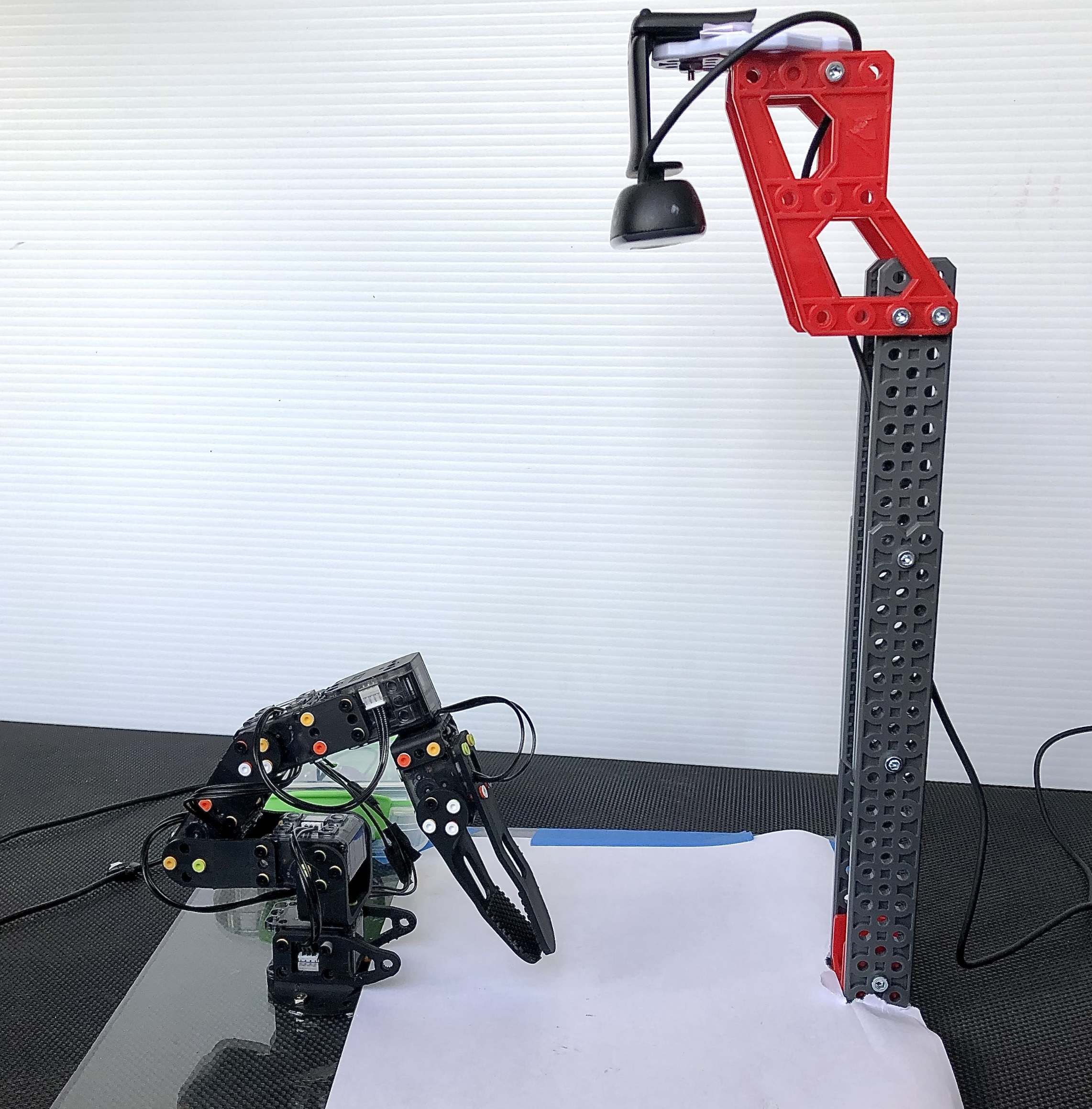 The robotic arm sits on a platform with a camera facing down at the platform